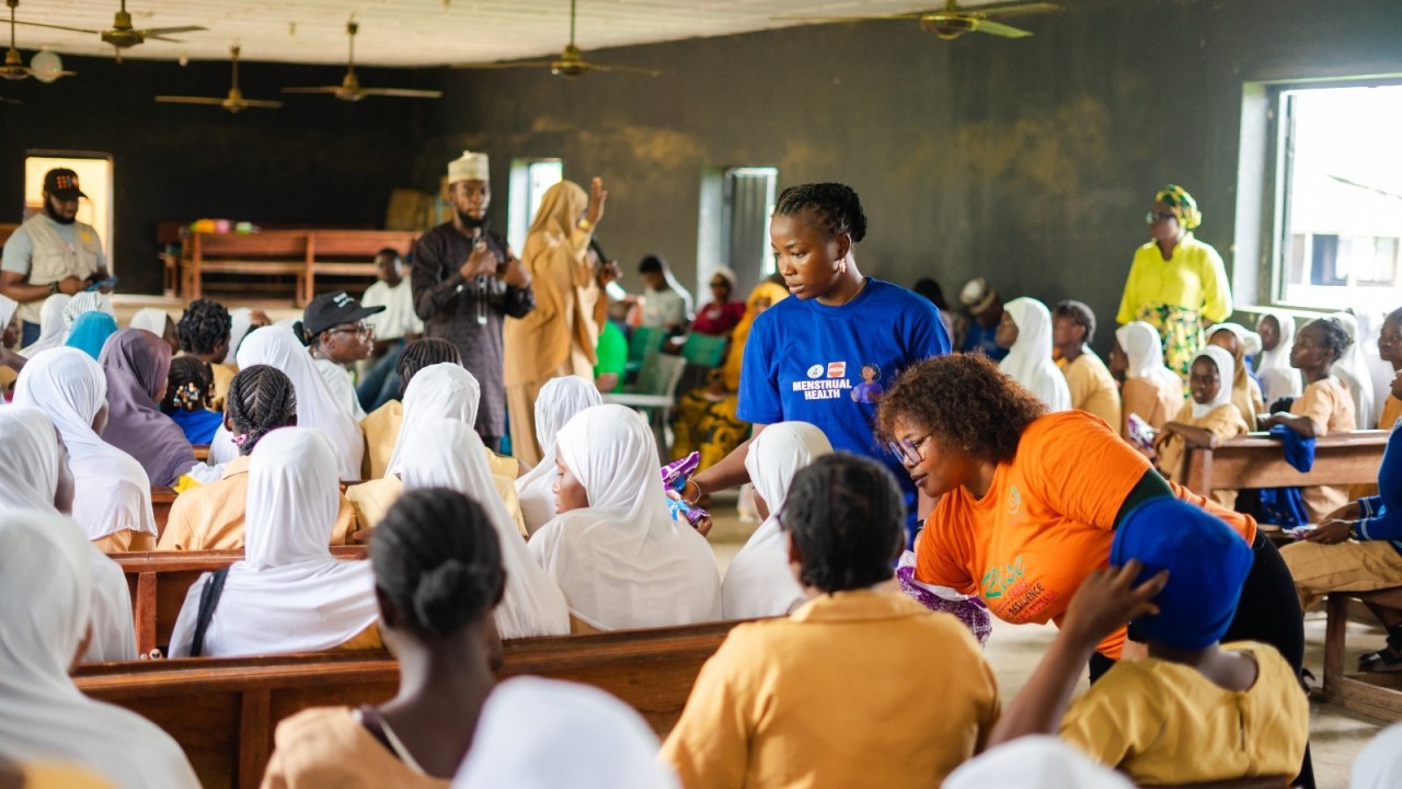 SFH staff in a school classroom distributing menstrual-health items to adolescent girls during a #PeriodFriendlyWorld outreach session