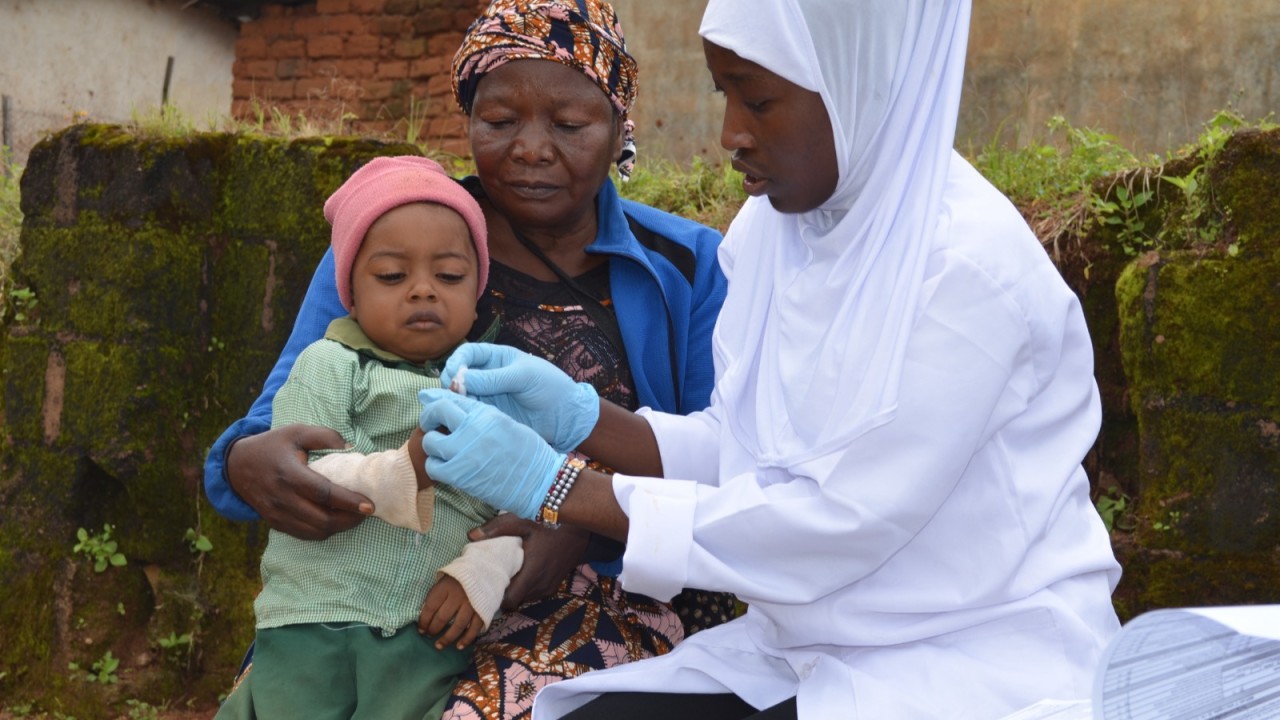A community health worker tests a baby held by a grandmother during a paediatric HIV outreach visit